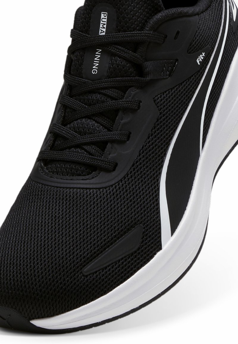 Zapatilla de entrenamiento negra con parte superior de malla, cierre de cordones y cuello acolchado. Presenta un acento blanco y una suela de goma texturizada para mayor tracción.