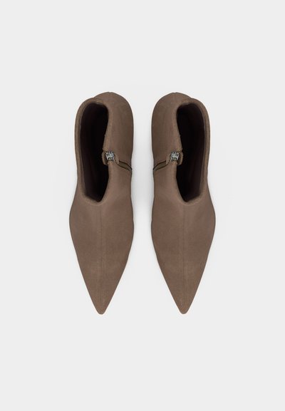 Ζευγάρι καφέ μπότες αστραγάλου με μυτερή μύτη και πλαϊνά φερμουάρ, από πάνω, σε λευκό φόντο.