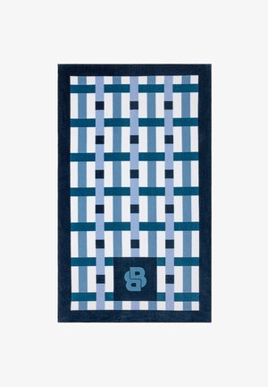 Tapis rectangulaire avec un motif géométrique en grille dans des tons de bleu et blanc, avec une bordure bleu foncé et un logo "B" stylisé.