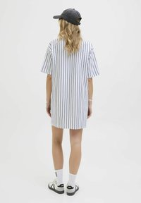 Robe chemise rayée en blanc et marine, manches courtes, coupe décontractée, avec un ourlet droit et une longueur au dos au-dessus des genoux.