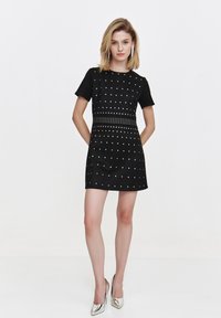 Black short-sleeve dress with silver studs and a studded waistband, featuring a fitted silhouette and smooth texture.