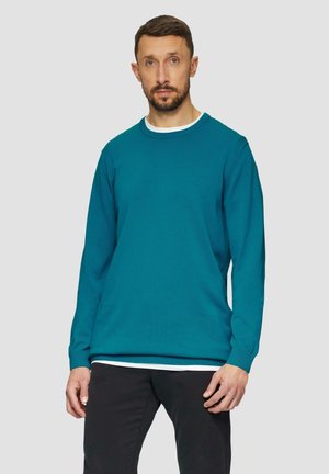 Teal trui met een ronde hals, lange mouwen en geribde manchetten. Witte binnenkraagdetail. Gekozen in combinatie met zwarte broek.
