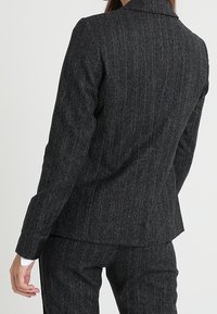 Ušitý šedý pruhovaný blazer z texturované látky, s klopovým límcem a dlouhými rukávy, s přiléhavým střihem a čistými liniemi.