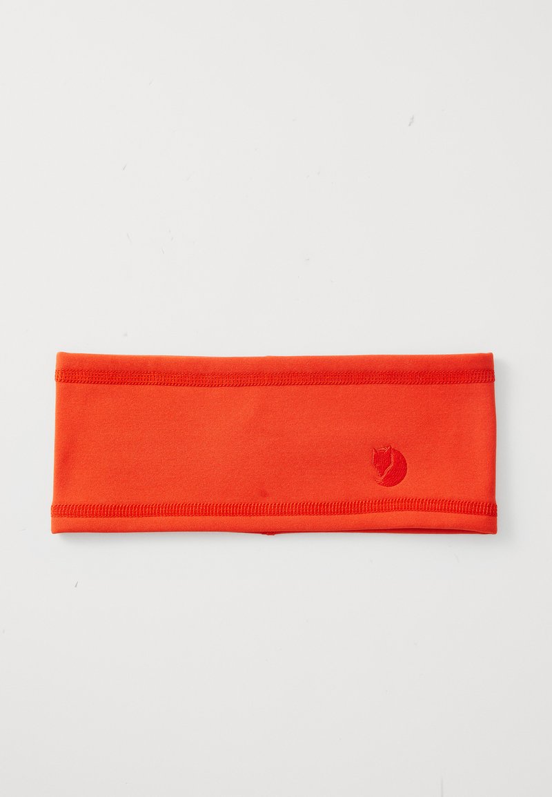 Bright orange fabric headband with stitched edges and a small fox logo embroidered on one side, laid flat on a white surface.