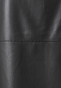 Zwart lederen materiaal met een gladde textuur. Bevat een horizontale naadlijn met subtiele stiksels. Geen patronen of metalen onderdelen zichtbaar.