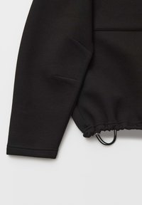 Felpa nera con finitura testurizzata, caratterizzata da un fondo arricciato con elementi regolabili e maniche dal taglio ampio e comodo.