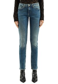 Niebieskie dżinsy z denimu o dopasowanym kroju, z efektem sprania, pięcioma kieszeniami i zamkiem błyskawicznym. Dopełnione czarnymi spiczastymi botkami za kostkę.
