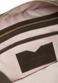Interno di una borsa in camoscio marrone, con una fodera in tessuto rosa chiaro e un compartimento con zip con accessori in metallo color oro.