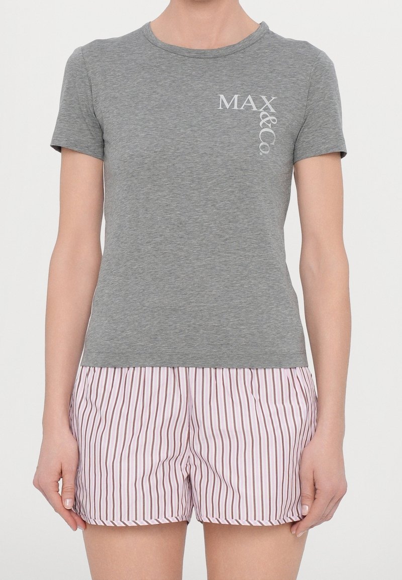 Femme portant un t-shirt gris à manches courtes avec le texte "MAX&Co." et un short à rayures verticales roses et blanches.