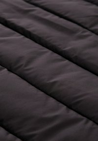 Czarna podszewka materiału z pikowanym wzorem. Powierzchnia wydaje się gładka z lekkim połyskiem, z poziomymi liniami stębnowania i subtelną teksturą.