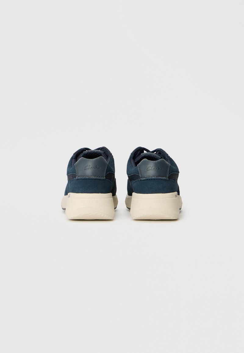 Granatowe zamszowe sneakersy z wzmocnionym piętą, kremową gumową podeszwą i wytłoczonym logo z tyłu dla dodatkowego efektu.