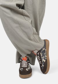 Leopard-print sneakers with brown suede, gray accents, and tan rubber soles. Contrasting orange detail on tongue, textured fabric upper.