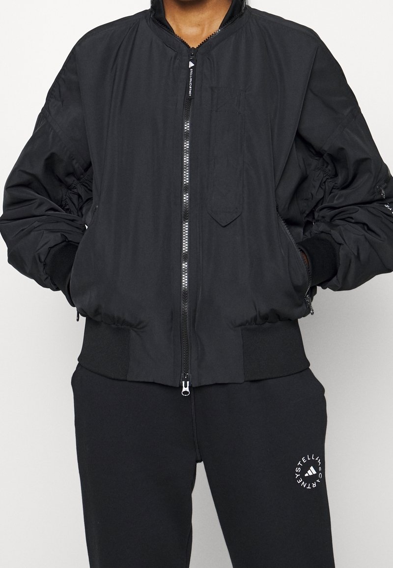 Black bomber jacket with zip closure, ribbed cuffs and hem, elasticated details on sleeves, front pocket, and lightweight fabric.