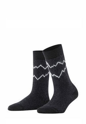 Paire de chaussettes noires texturées avec motif en zigzag blanc près du haut, avec des parties unies noires aux orteils et aux bordures.