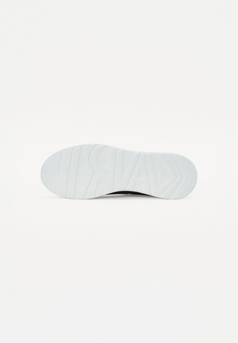 Semelle de basket blanche avec des rainures et motifs texturés ; présente des bords arrondis ; profil plat ; design minimaliste sans logos ni accents.