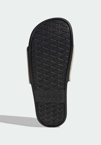 Semelle en caoutchouc noir avec un motif texturé pour une meilleure adhérence. Présente un logo "adidas" sur la surface. Bords arrondis, profil plat.