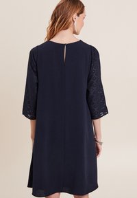 Marineblaue Kleid mit drei Viertel langen Spitzenärmeln, Rückenschlüssellochdetails und einem lockeren Schnitt, aus leichtem Stoff gefertigt.
