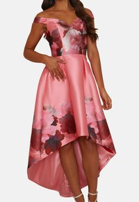 Růžové saténové šaty s odhalenými rameny, květinovou živůtkou a asymetrickým lemem. Skirt má červené a růžové květinové vzory.