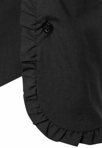 Black fabric garment featuring a ruffled edge and a single black button detail, highlighting smooth texture and clean lines.