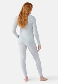 Helle blaue Langarmbluse mit leicht strukturiertem Stoff und tailliertem Design, kombiniert mit passenden High-Waist-Leggings.