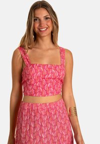 Top corto rosa con escote cuadrado y tirantes anchos, con un patrón de hojas. Combinado con una falda de cintura alta a juego.