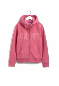 Sweat à zip rose avec poches avant, capuche et logo "GANT" embossé sur la poitrine, suspendu à un cintre blanc.