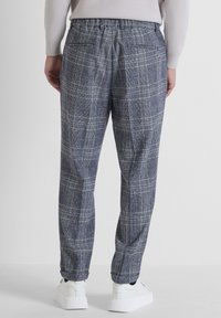 Karierte Hose in Marineblau und Grau. Aus gewebtem Stoff mit entspannter Passform. Verfügt über einen elastischen Bund und zwei Gesäßtaschen.