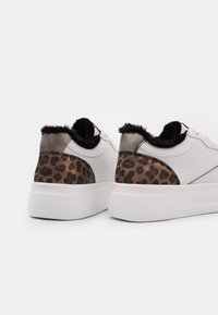 White sneakers with a textured leopard print back, gray accents, and a plush black fur collar. Thick white rubber sole.