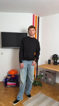 Mustmust, heledad sinised teksad, mustad tossud. Kaasaegne interjöör värviliste seinaribadega, teler, oranž lamp ja potitaim.