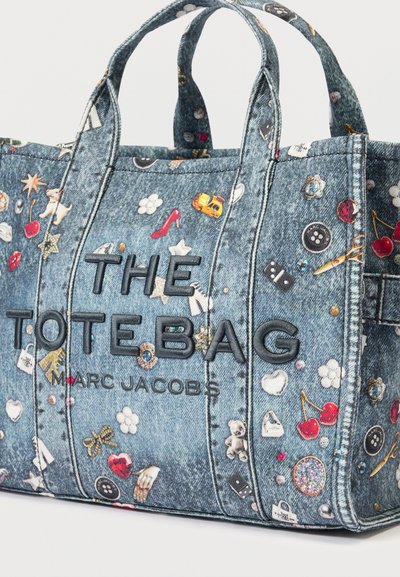 Denim draagtas met geborduurde tekst "THE TOTE BAG" en "MARC JACOBS", versierd met kleurrijke kleine iconen en patronen.