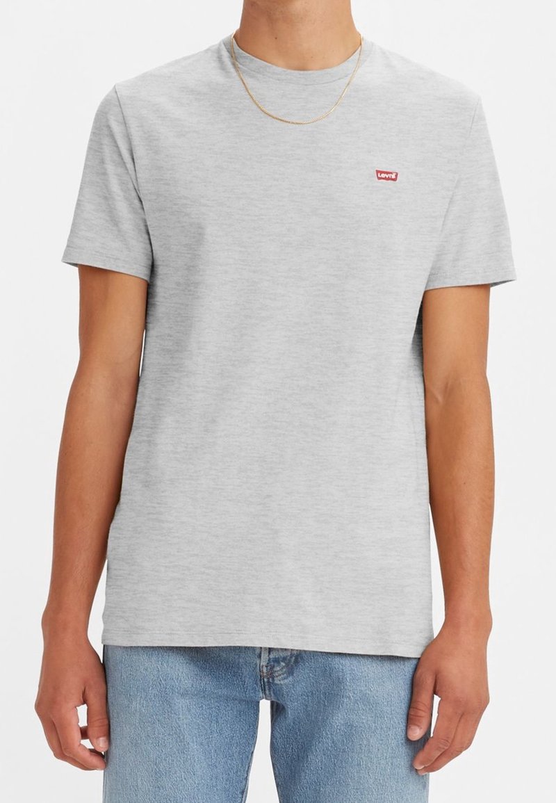 T-shirt grigio a maniche corte realizzato in tessuto morbido, con un piccolo logo rosso Levi's sul petto, abbinato a jeans denim blu chiaro.
