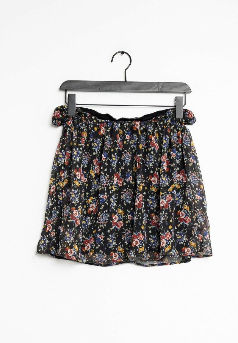 Jupe florale avec un fond noir et des motifs de fleurs colorées, fabriquée en tissu fluide et froncée à la taille avec une bordure noire.