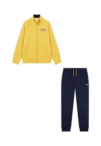 Chaqueta amarilla con cremallera y logo, bolsillos frontales, y pantalones de chándal azul marino con cordón ajustable y logo en el lateral.