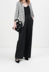 Gray plaid blazer, black camisole, high-waisted black trousers, and pointed black heels. The outfit features structured lines and varied textures.