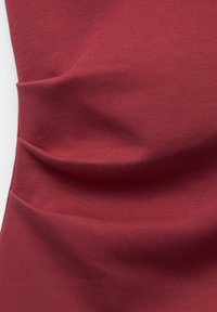 T matagalia burgundy cu o textură moale, având detalii pliate și o suprafață netedă. Materialul pare elastice și se potrivește strâns.