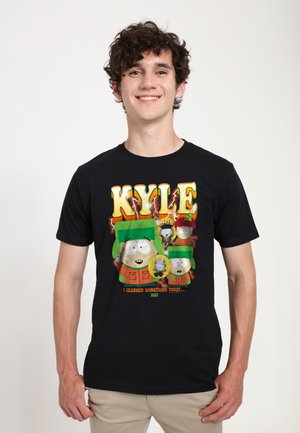 Young man wearing a black t-shirt featuring South Park character Kyle with green hat and orange coat, text "KYLE" and "I learned something today."