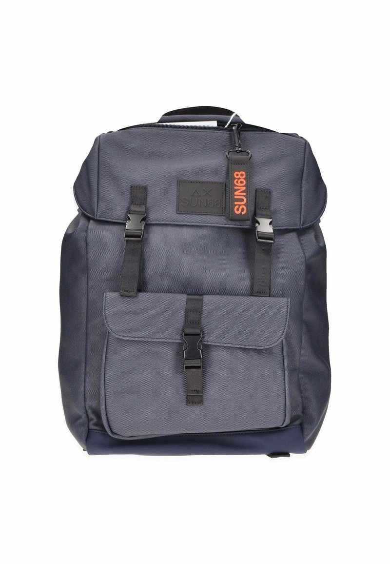 Zaino grigio scuro realizzato in tessuto resistente. Presenta spallacci regolabili, una tasca frontale con gancio e un'etichetta con il logo arancione.