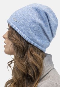 Bonnet tricoté bleu chiné au design décontracté et à la finition texturée, avec un accent en argent près de l'ourlet.