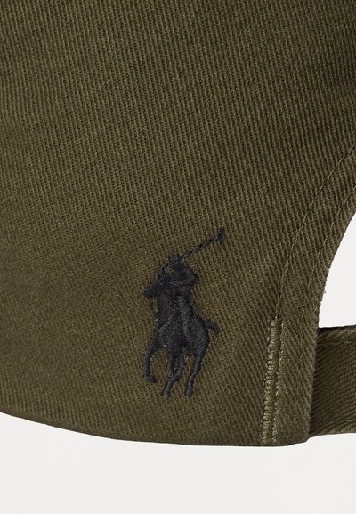 Căciulă verde măslinie dintr-un material texturat. Prezintă un logo brodat cu un cal și un călăreț pe partea din față. Curea ajustabilă la spate.