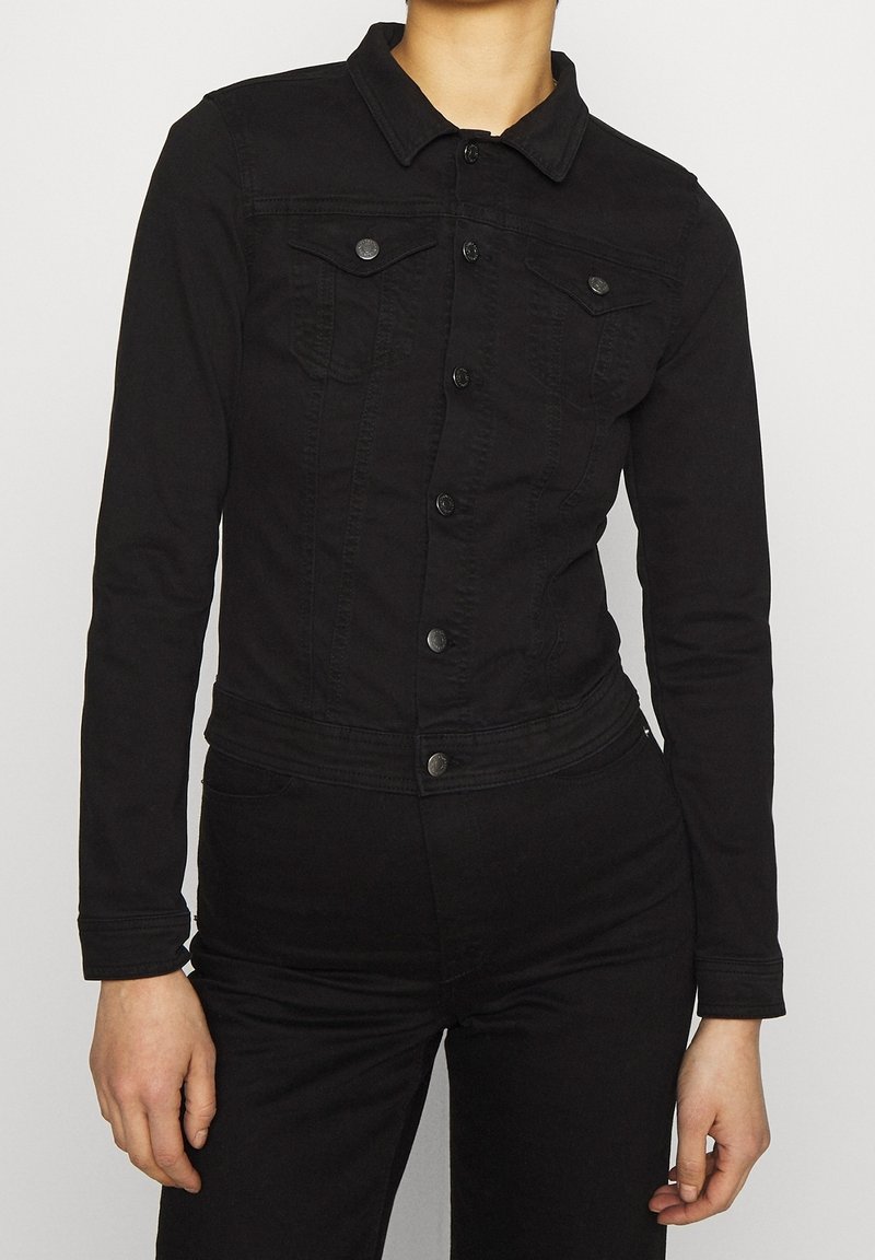 Chaqueta de mezclilla negra con mangas largas, cierre de botones, bolsillos en el pecho y cuello, con un diseño ajustado y tejido texturizado.