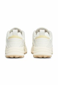 Scarpe sportive bianche con materiale in rete e sintetico liscio, tacchi rotondi e suole testurizzate. Accenti minimi in giallo e grigio.