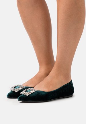Ballerines en velours vert, à bout pointu et ornées d'un bijou sur le devant, dotées d'une texture lisse et d'une semelle plate.