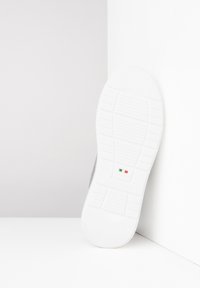Baskets grises avec une tige en cuir texturé. Elles disposent d'une semelle en caoutchouc blanc avec des motifs de bande de roulement et d'un petit détail de drapeau italien.
