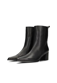Une paire de bottines noires en cuir lisse avec des bouts pointus, des talons bloc et des languettes à l'arrière, présentées sur un fond blanc.