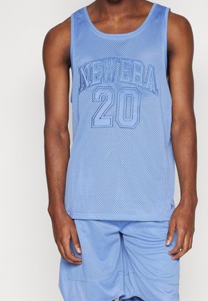 Hombre vestido con camiseta y pantalones cortos de malla de baloncesto de color azul claro con "NEW ERA 20" impreso en la parte frontal de la camiseta.