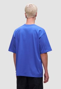 Koszulka z krótkim rękawem, okrągłym dekoltem w jasnoniebieskim kolorze z bawełny. Luźny krój, gładka tekstura, bez widocznych wzorów czy akcentów.