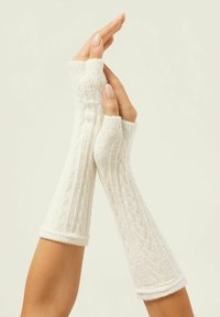 Fingerlose Handschuhe aus weißem Strickstoff mit einem strukturierten Zopfmuster und gerippten Bündchen, die bis zu den Unterarmen reichen.