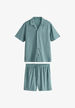 Měkká tyrkysová košile s krátkými rukávy a knoflíky, doplněná o krátké kalhoty se stahovací šňůrkou v pase, obojí vyrobené z froté látky.
