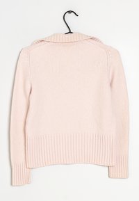 Maglione lavorato a maglia rosa chiaro con orlo e polsini a coste, caratterizzato da un colletto ripiegato e una trama sottile. Appeso a un gancio nero.