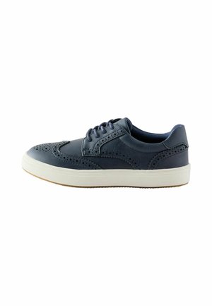 Marineblaue Leder-Brogue-Sneaker mit perforierten Details, dunklen Schnürsenkeln und einer weißen Gummisohle auf weißem Hintergrund.